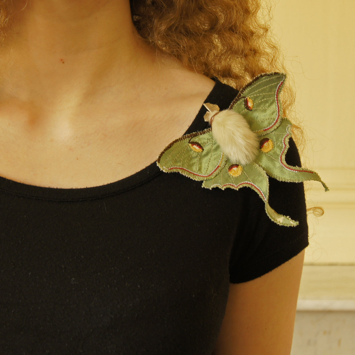 Model wears life-sized handmade fiber art Luna moth brooch  on her shoulder 