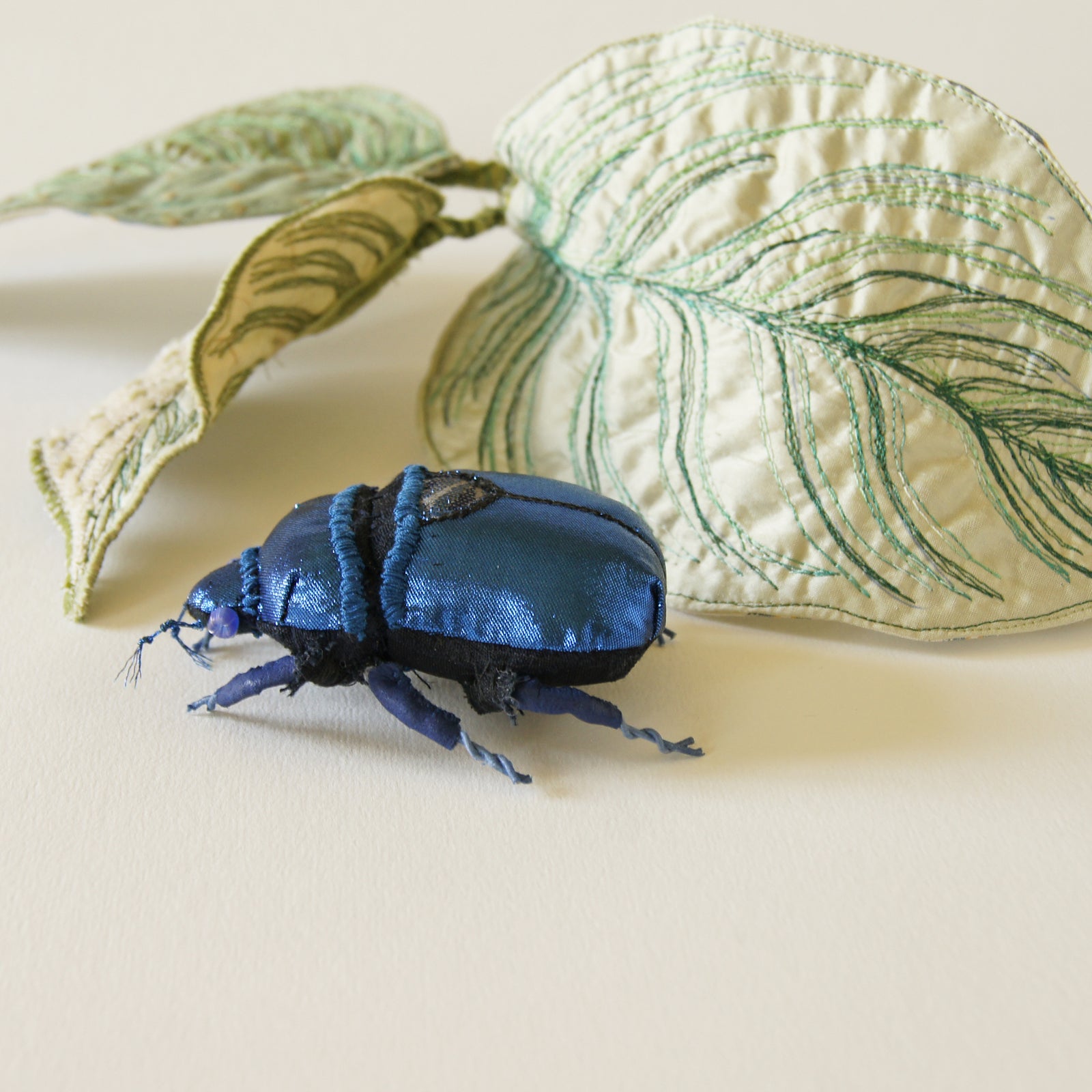 Blue jewel scarab and philodendron leaves textile sculpture