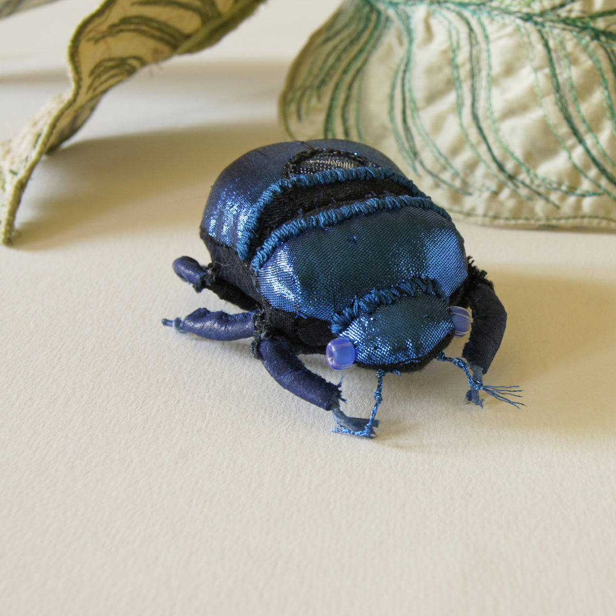 Blue jewel scarab and philodendron leaves textile sculpture