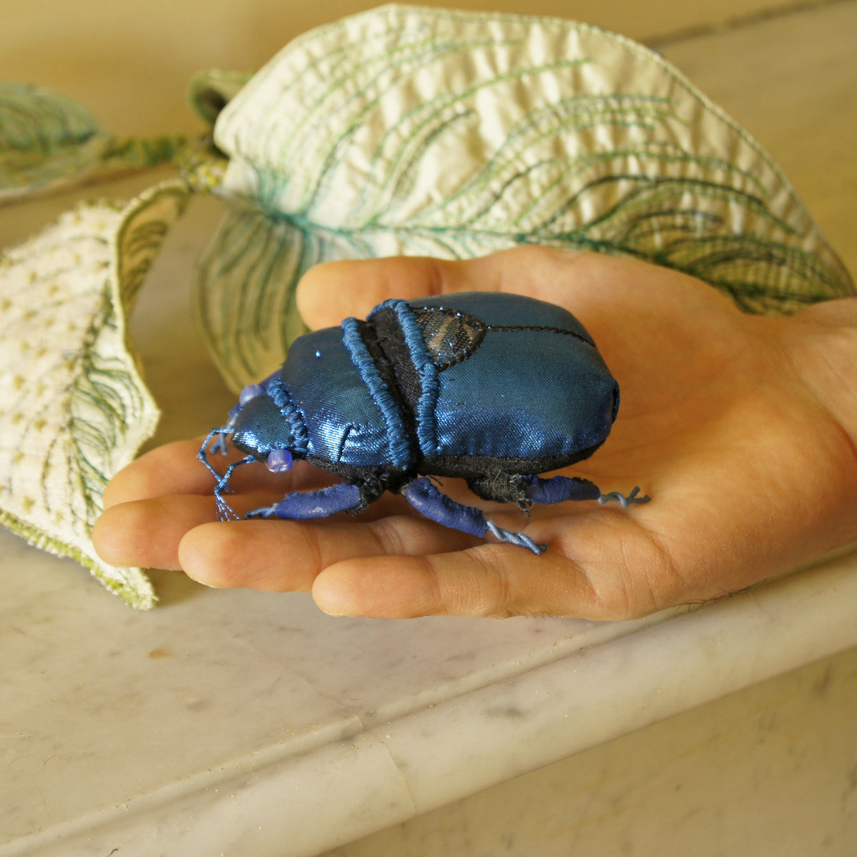 Blue jewel scarab and philodendron leaves textile sculpture