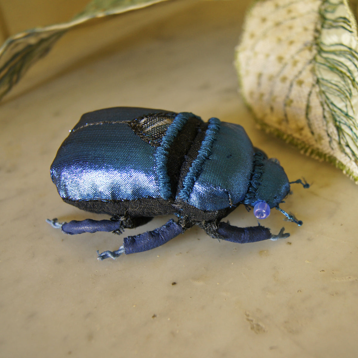 Blue jewel scarab and philodendron leaves textile sculpture